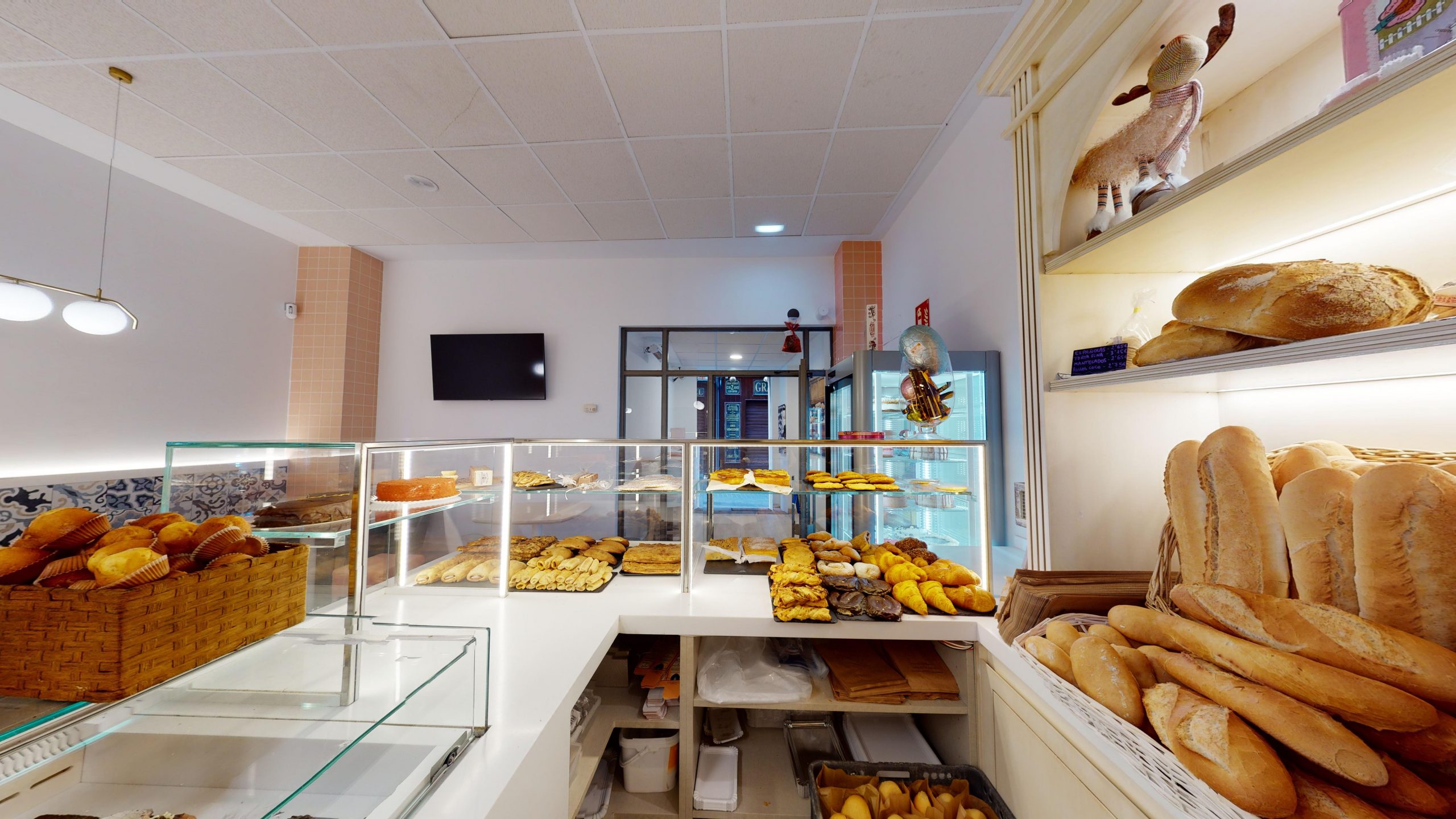 Imagen de la pastelería desde dentro del mostrador con productos y barras de pan 