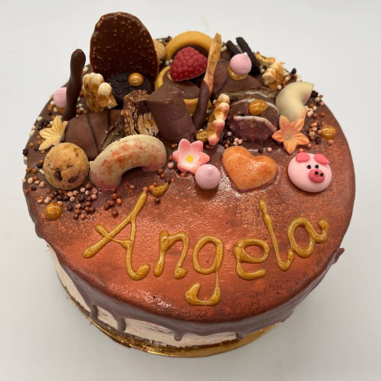 Imagen de una tarta que pone escrito ángela y es de color marrón como de chocolate con galletas encima de tarta de cumpleaños