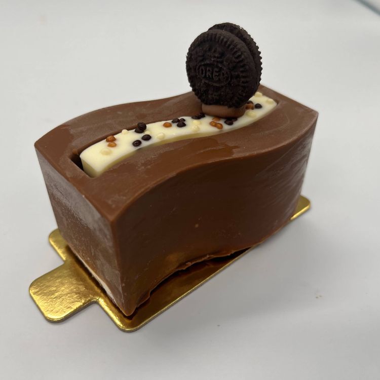 Imagen pastel de chocolate con forma de onda y una galleta oreo encima 