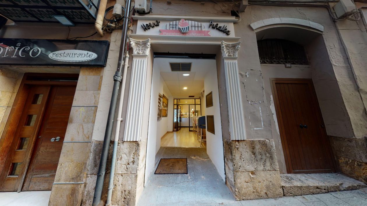 Imagen de la pastelería desde el exterior con la entrada en la calle y el cartel de la pastelería arriba